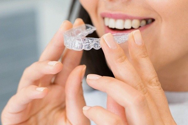 Jovem sorrindo com aparelho ortodôntico discreto na Click Dente